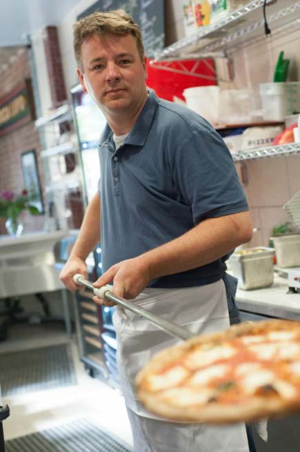 Owner of Pizza Bocca Lupo holding a pizza peel